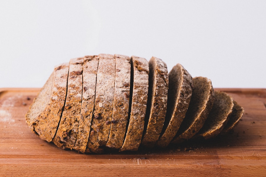 A sliced rustic loaf with a flour-dusted crust on a wooden chopping board